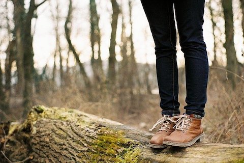 Kvinna står på stock i skogen